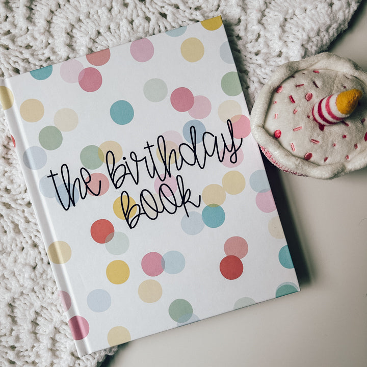 Birthday memory book covered in green, pink, blue, and yellow polka dots titled The Birthday Book in black text.