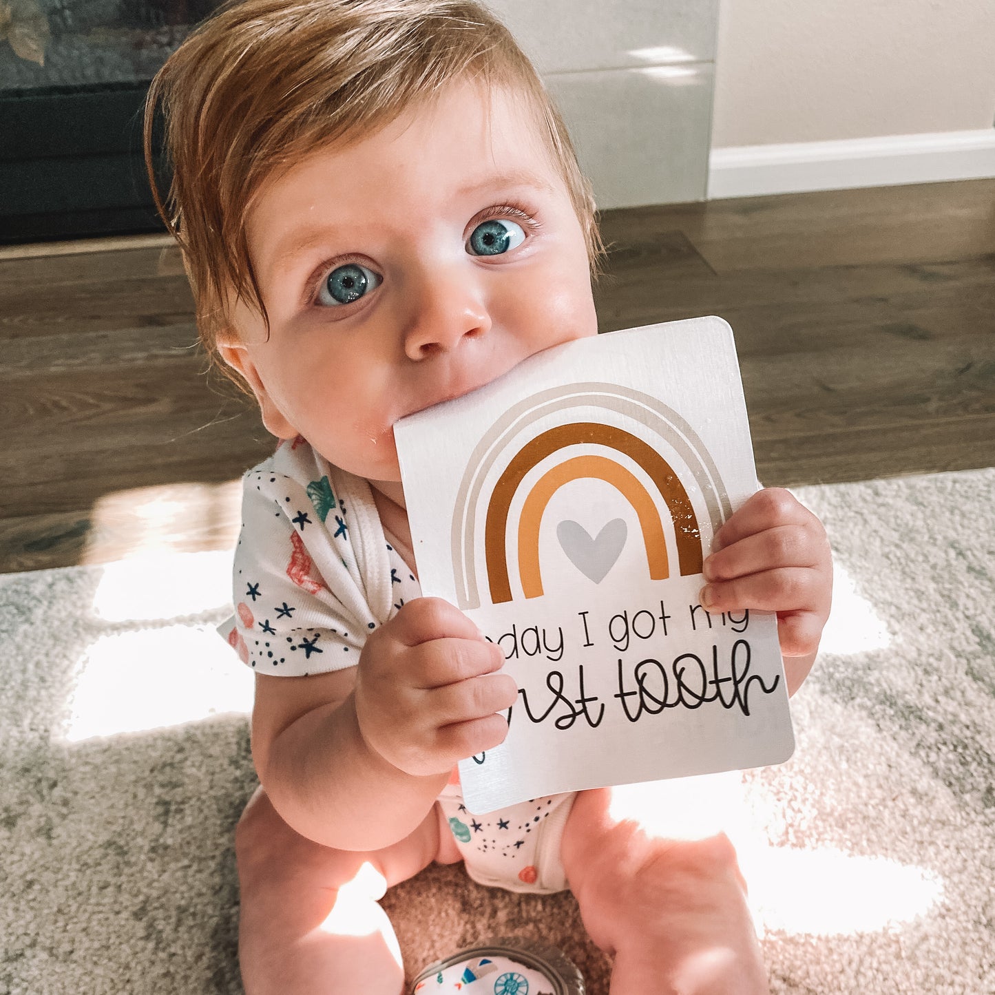 Baby holding today I got my first tooth milestone card. Card has a rainbow above text