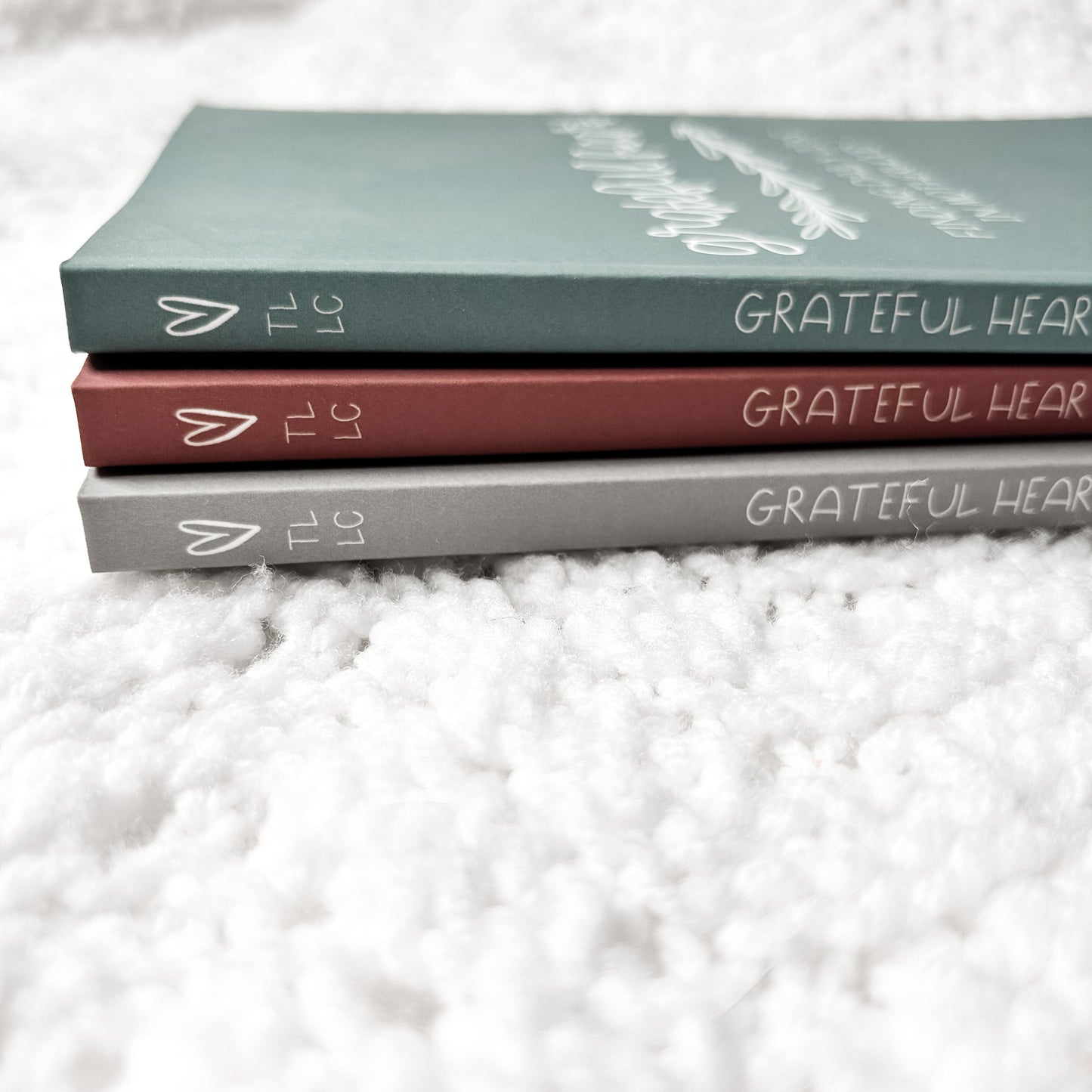 Side view of paperback journals has a heart, TLLC, and Grateful Heart printed on the spine