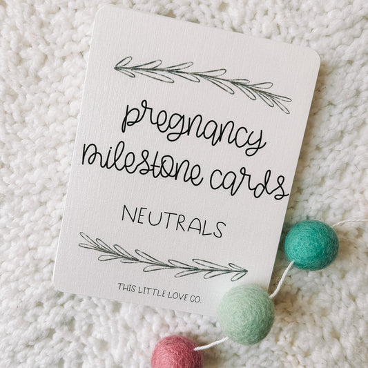 Card with black text that reads pregnancy milestone cards neutrals. There is an image of a leafed branch above and below the text and the text This Little Love Co at the bottom of the card.