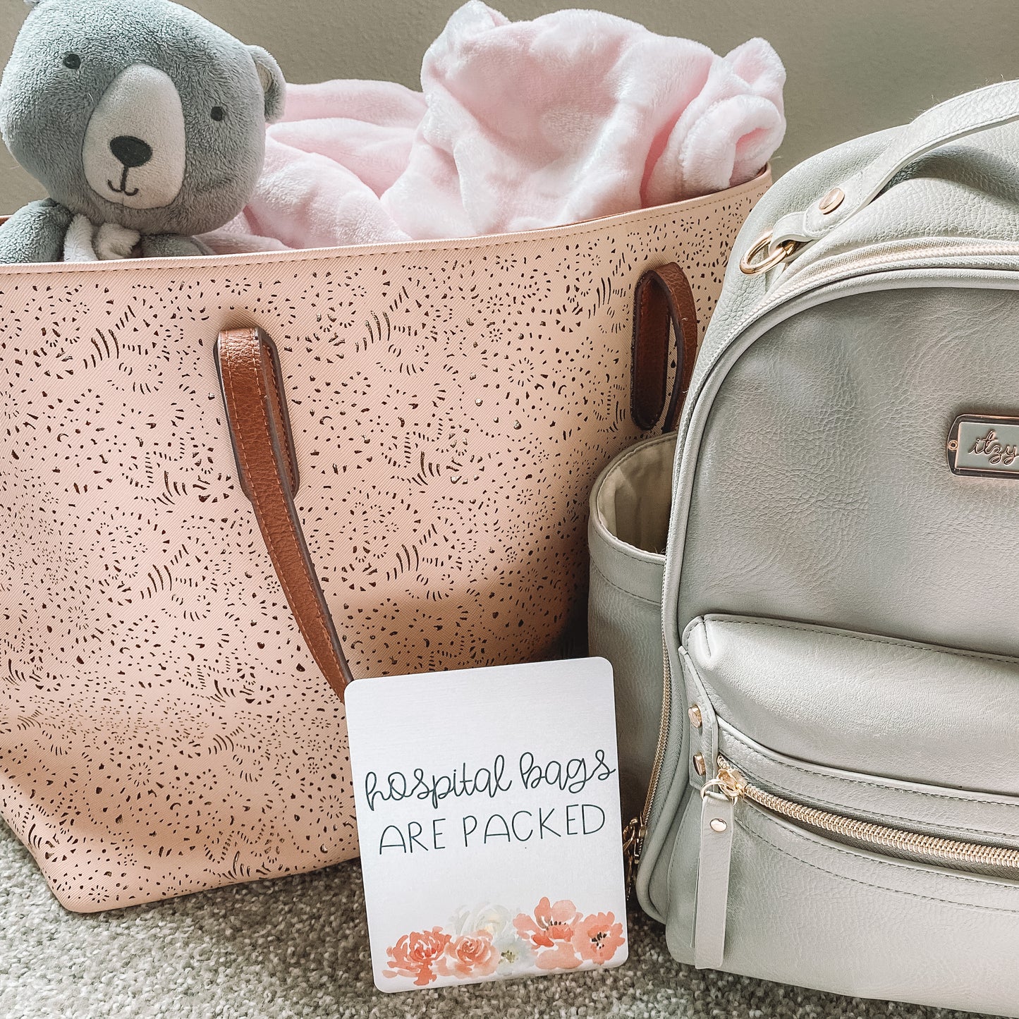Milestone card that reads hospital bags are packed in front of two bags.