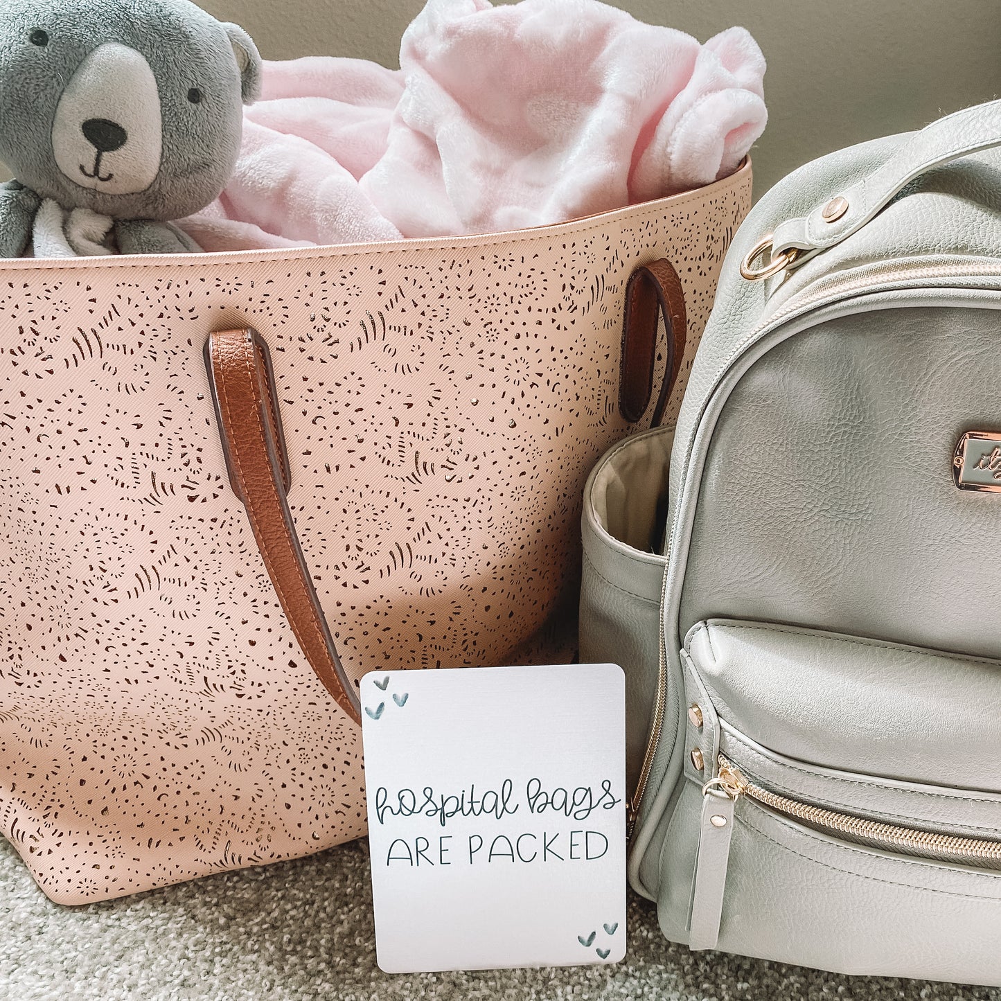 Milestone card that reads hospital bags are packed in front of two bags.