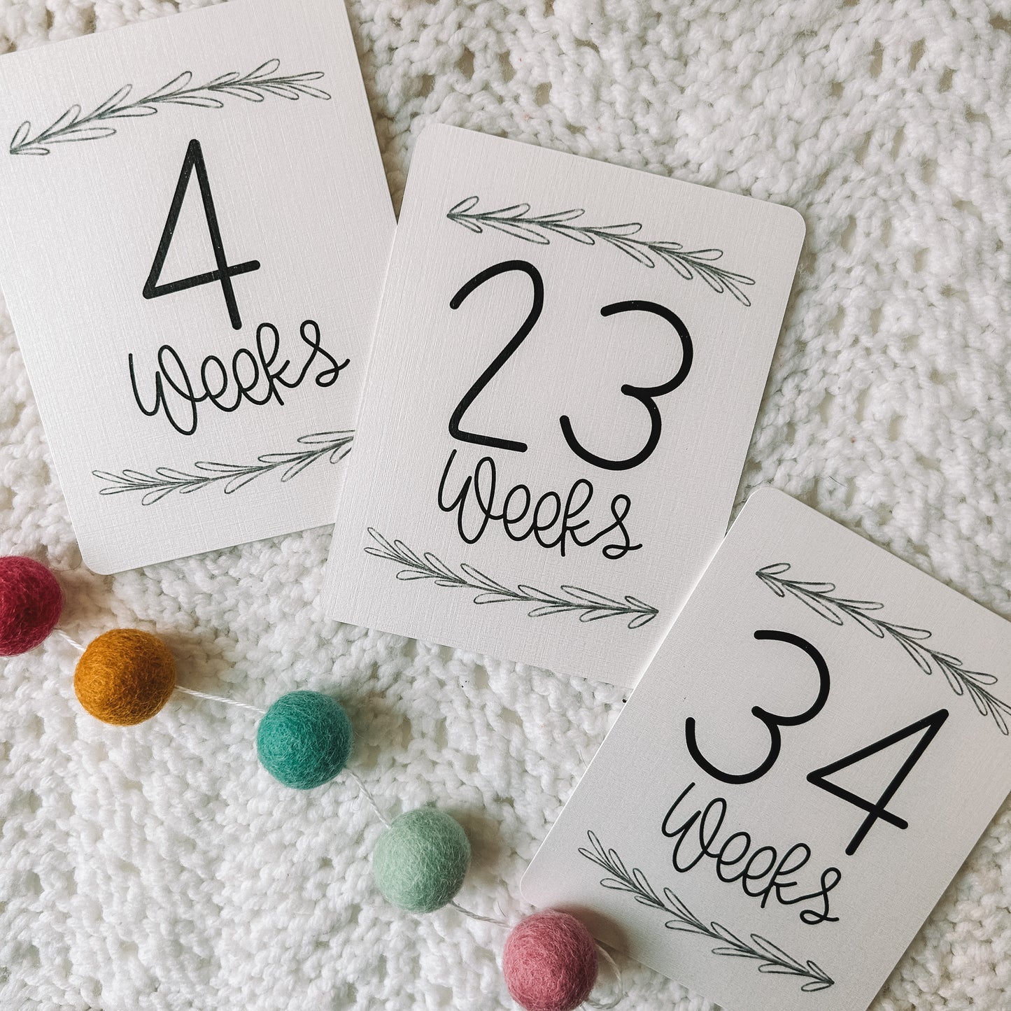 Three cards that read 4 weeks, 23 weeks, and 34 weeks with a leafed branch above and below the black text.