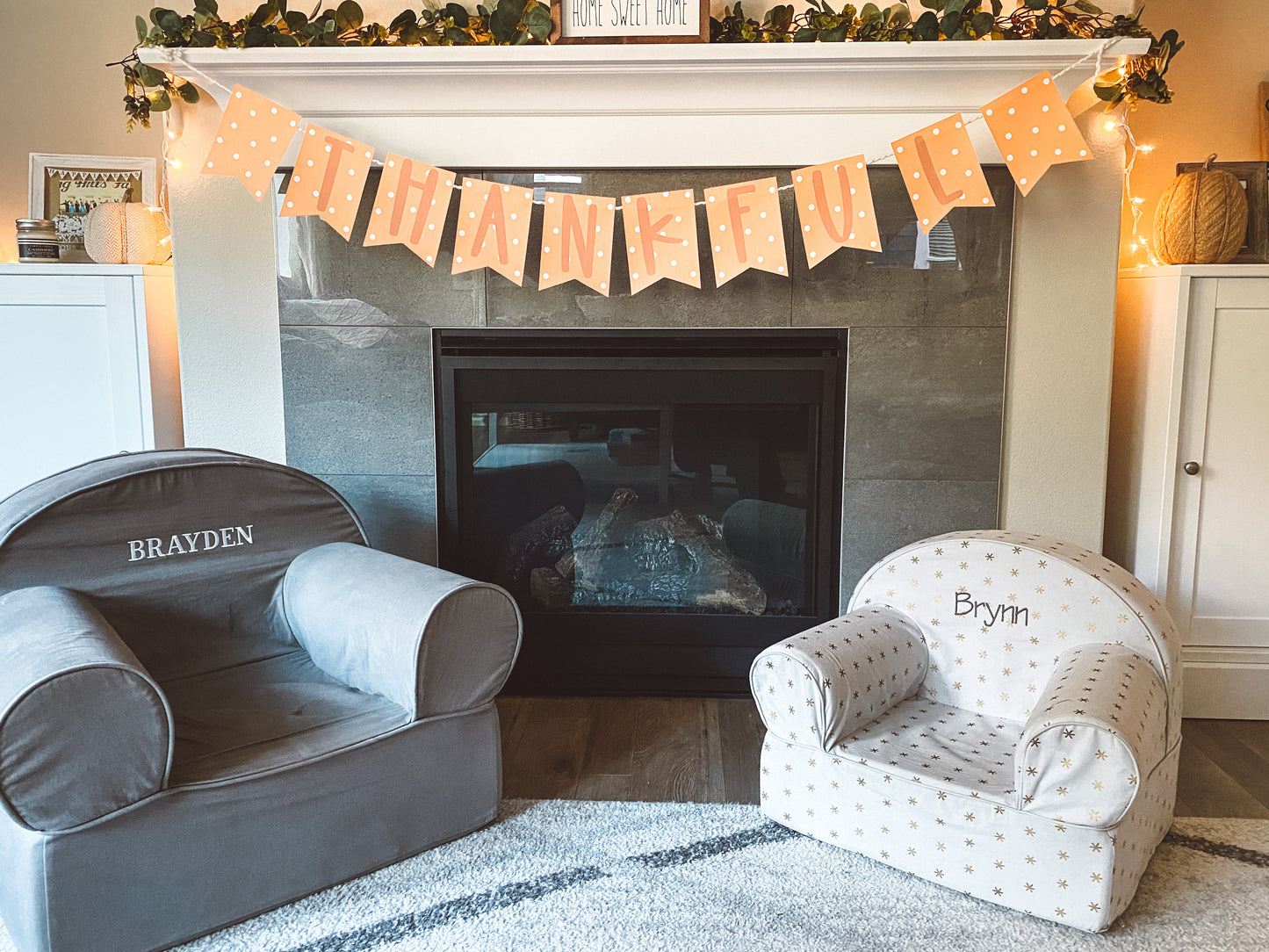 Shows thankful banner hanging on the mantle. The banner has light orange background with white polka dots on each pennant. Darker orange text spells out thankful. One letter on each pennant.