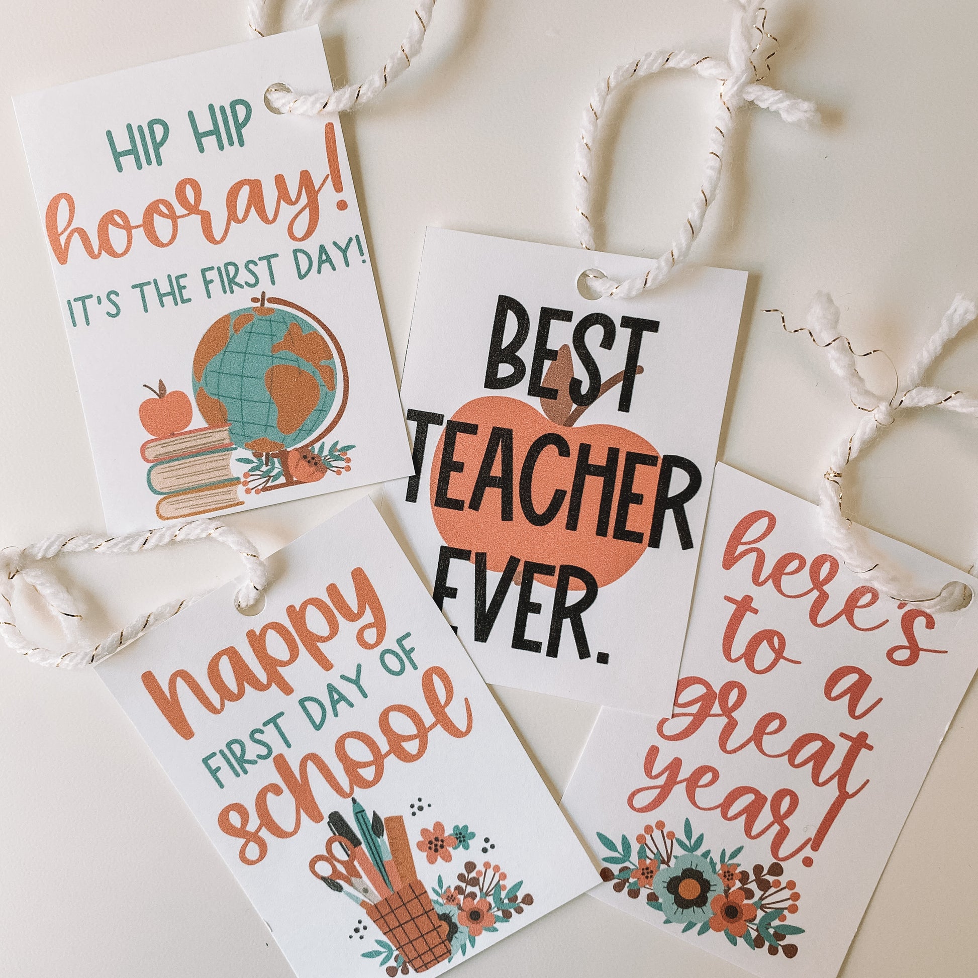 Four designs of teacher gift tags hole punched with a ribbon looped through.