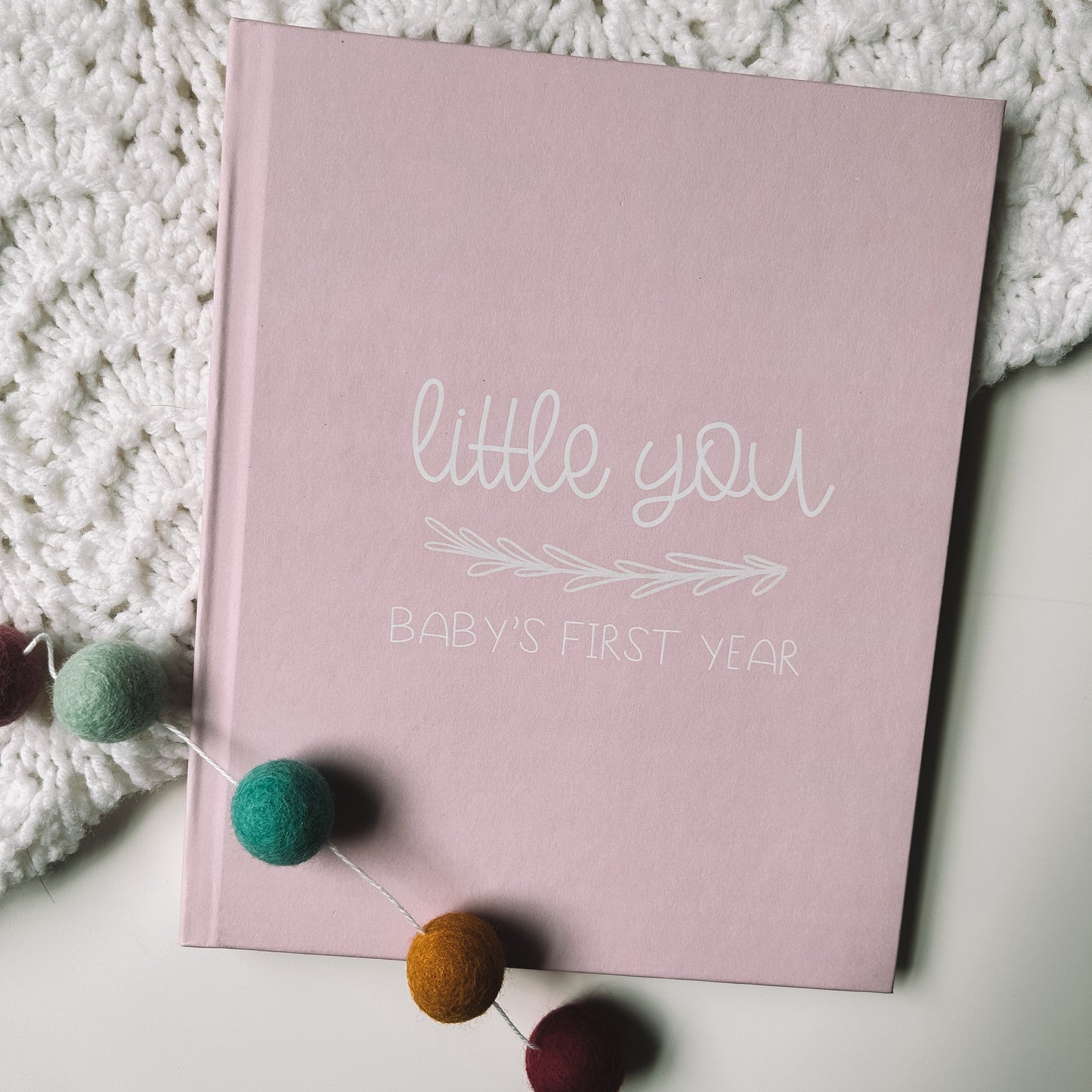 Keepsake baby book with a pink cover titled Little You Baby's First Year in white text.