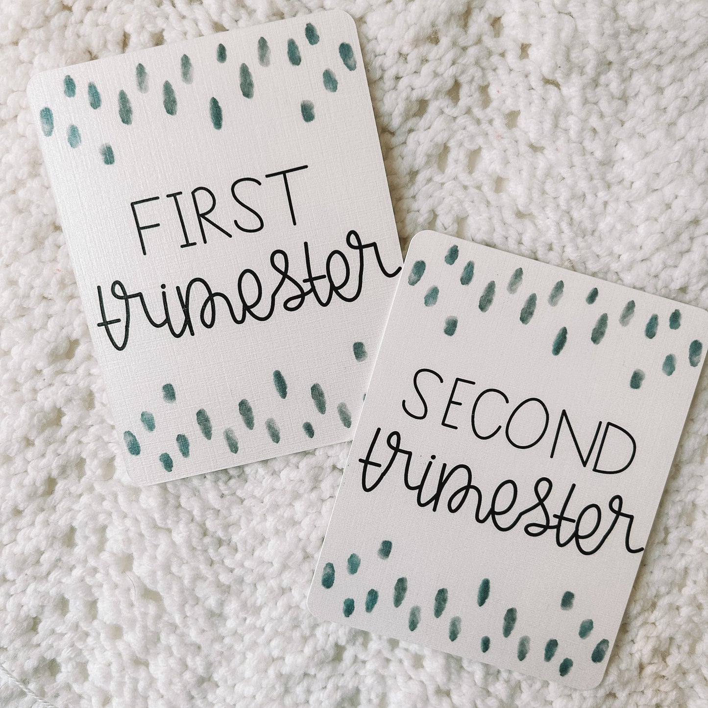 Two milestone cards with black text and blue dots above and below the words first trimester and second trimester