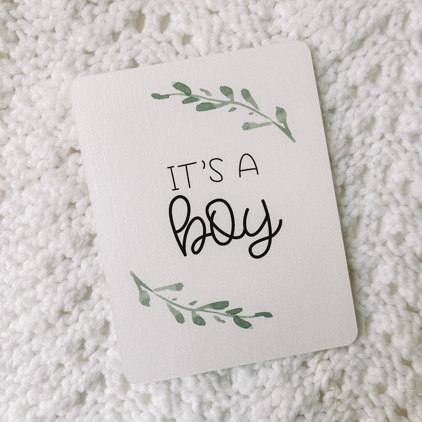 Milestone card with the text it's a boy and leafed branches around it.
