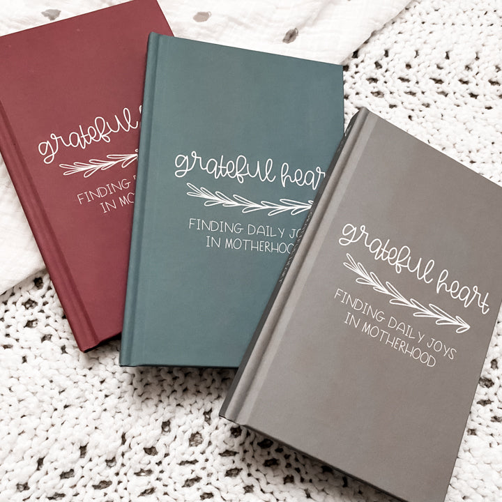 Blue, maroon, and grey gratitude journals titled Grateful Heart Finding Daily Joys in Motherhood