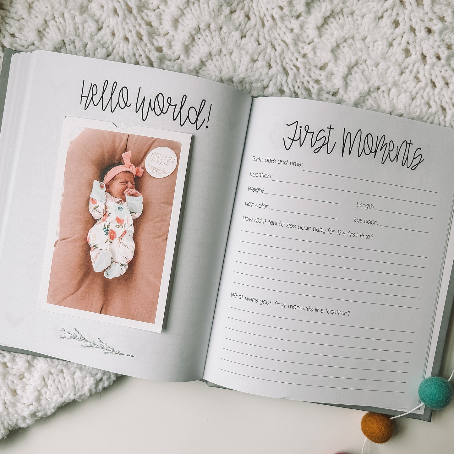 Two page spread with one page titled Hello World with photo of a newborn baby. The page on the right is titled First Moments with space fore birth details and two prompts.
