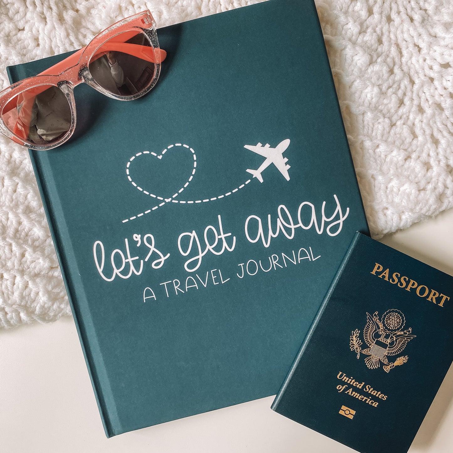 Keepsake travel journal with a soft, matte blue hardcover. White text reads Lets Get Away A Travel Journal with a graphic of a white airplane leaving a heart trail behind it.
