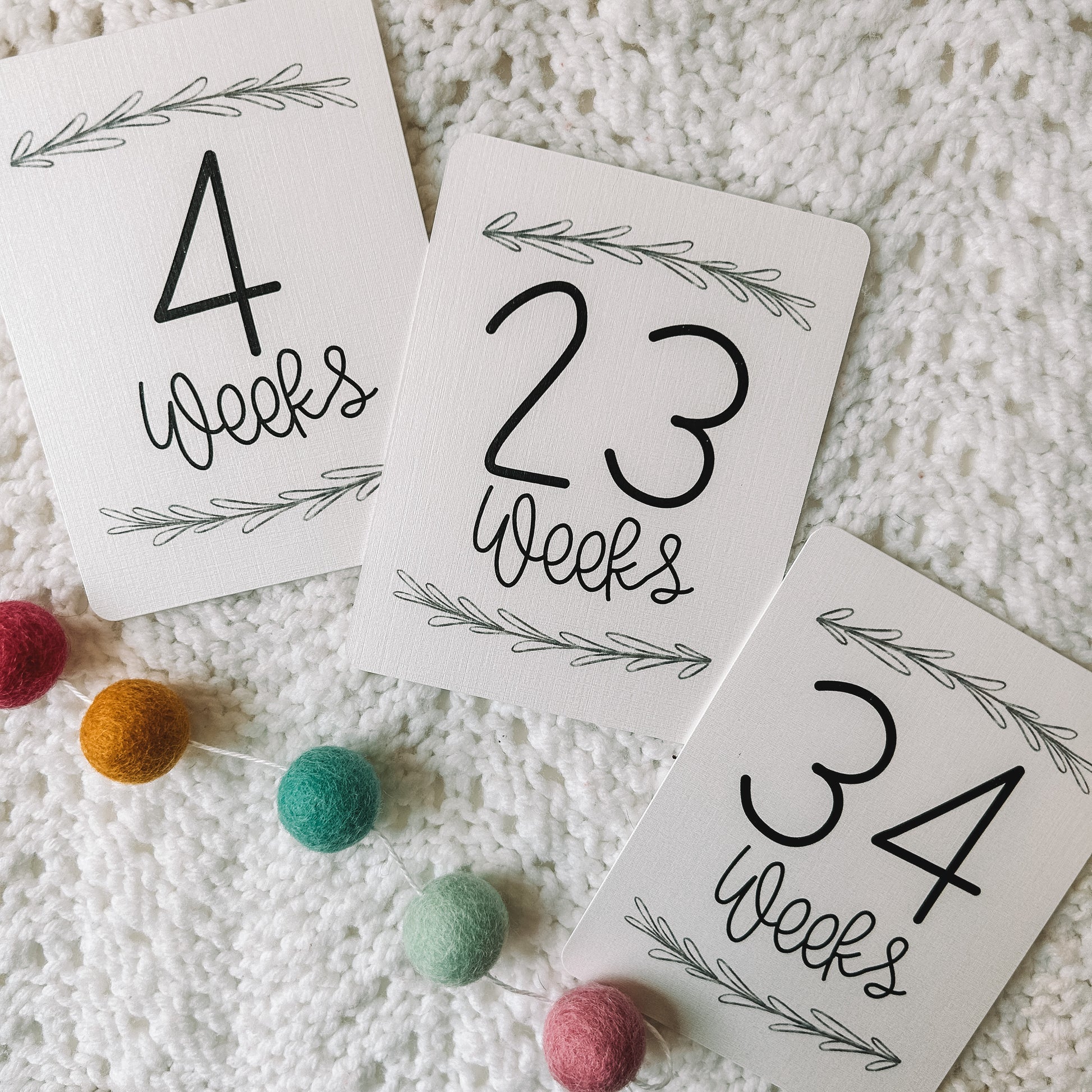 Three cards that read 4 weeks, 23 weeks, and 34 weeks with a leafed branch above and below the black text.
