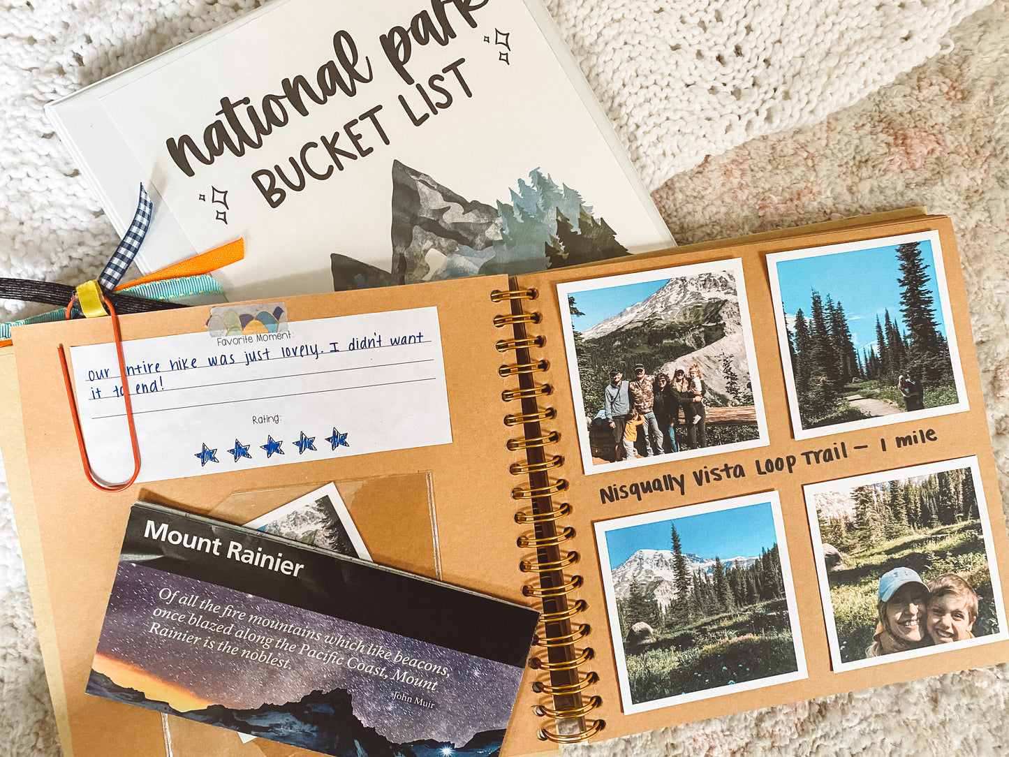 Interior page of scrapbook shows square photos of National Park trip pasted on one page. A plastic pocket with a Mount Rainier map and part of the National Parks printable with the rating is pasted on the other side.