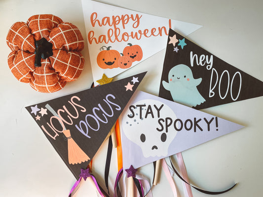 Four Halloween pennant flags in a flat lay with with an orange pumpkin.