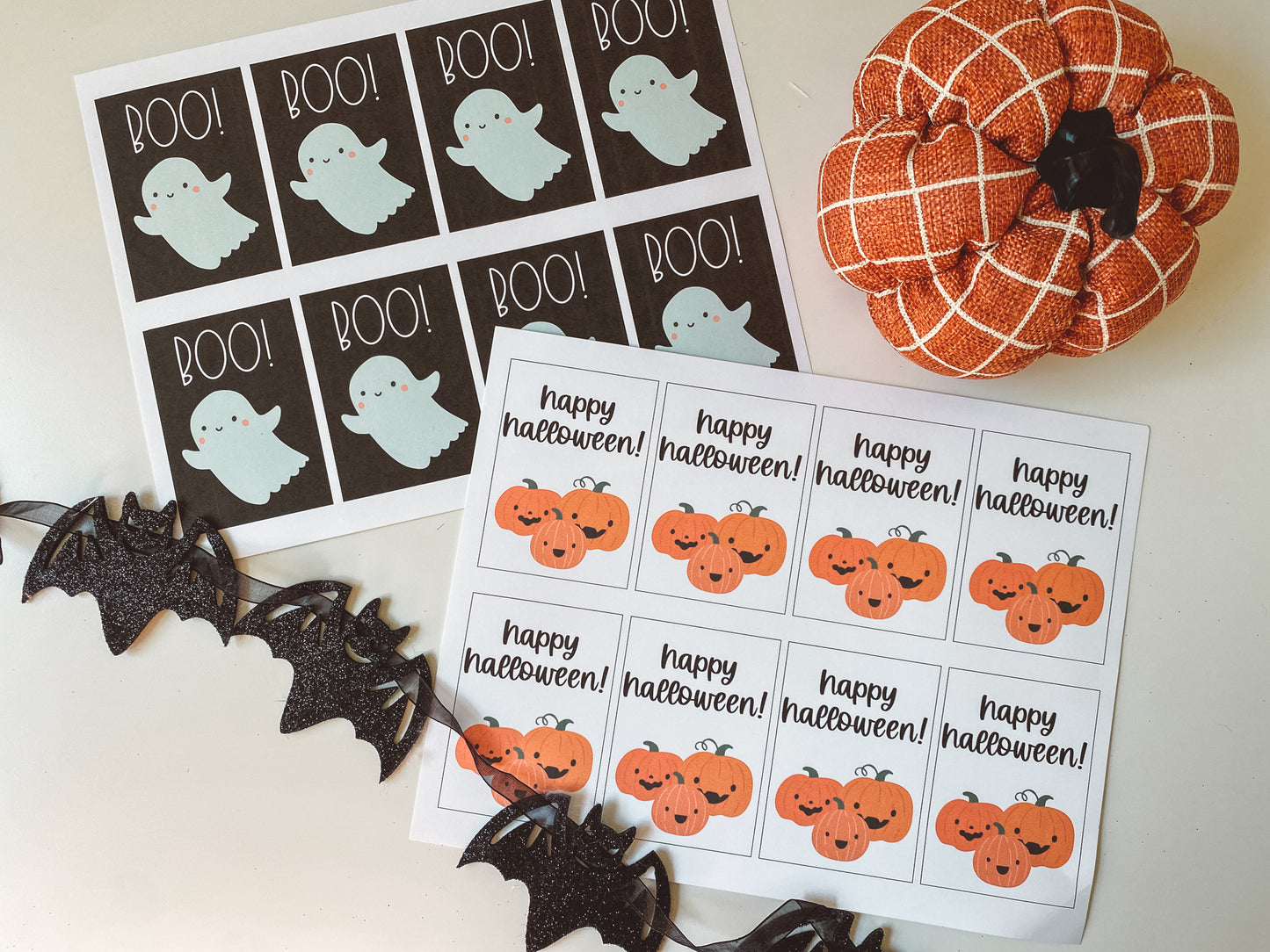 Boo and happy halloween gift tags displayed as they look when printed. 8 tags fit on an 8.5 by 11 inch page. Boo tags have a black background with a bluish white ghost. Happy halloween has a white background with black text and three orange pumpkins